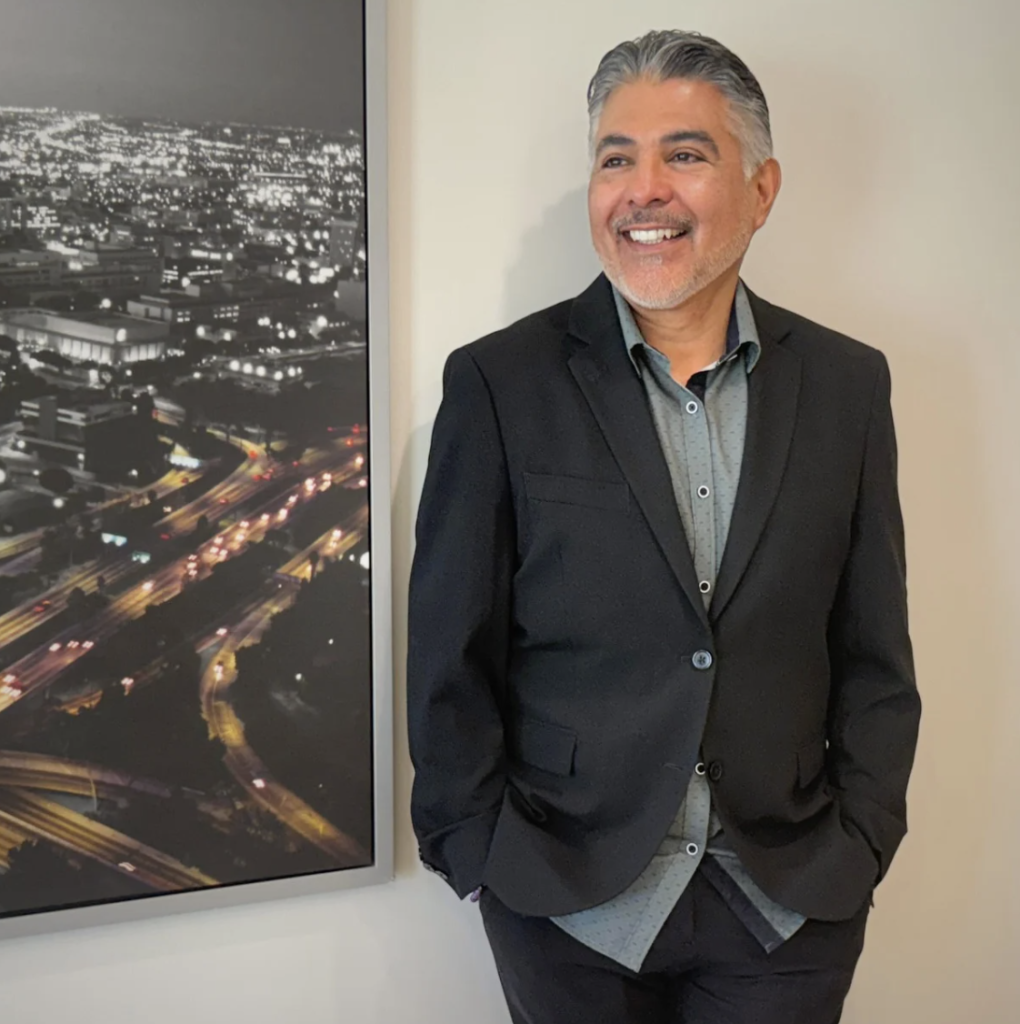 Tony Cárdenas smiling next to a photo on wall