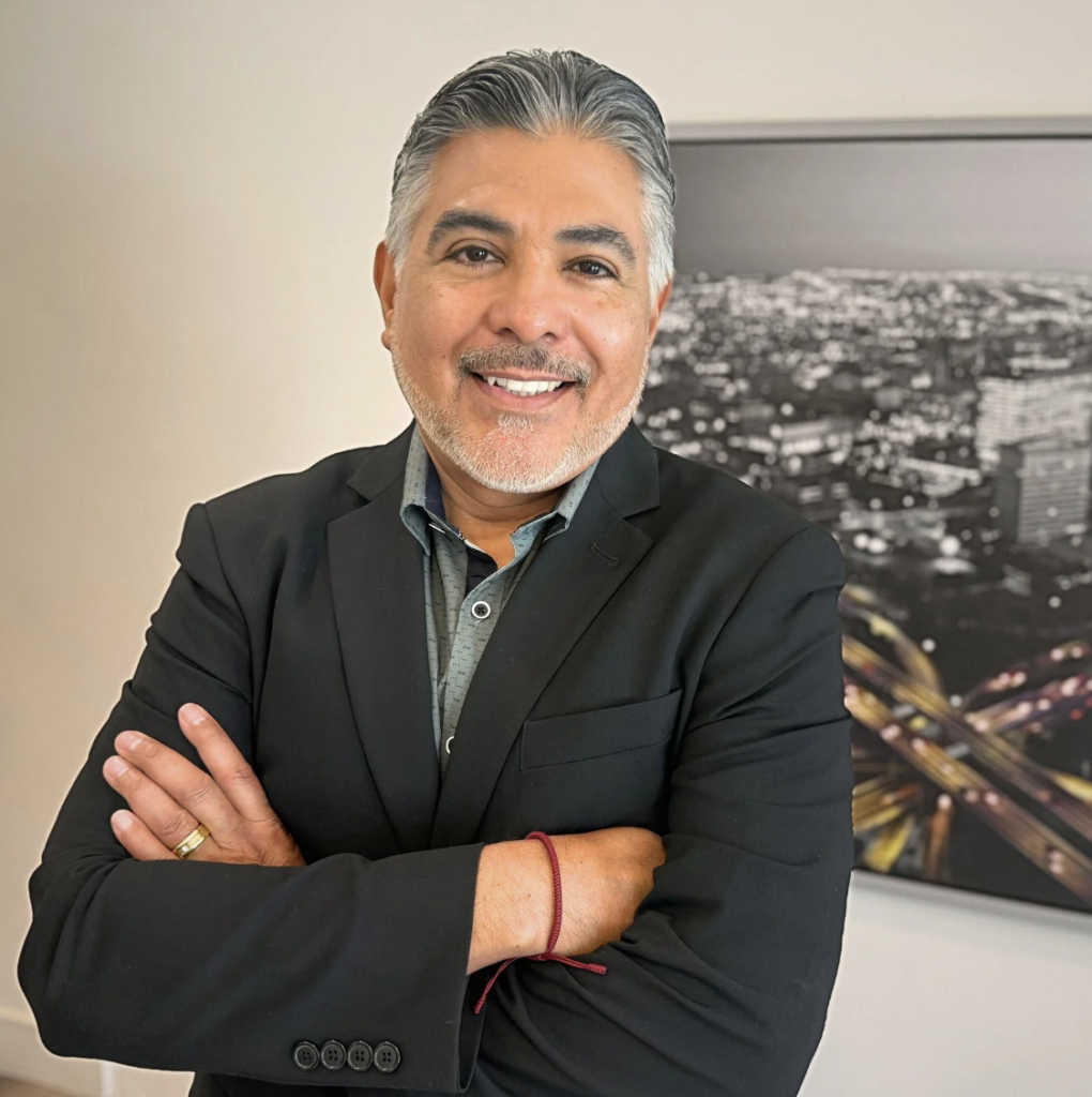 Tony Cárdenas smiling next to a photo on wall